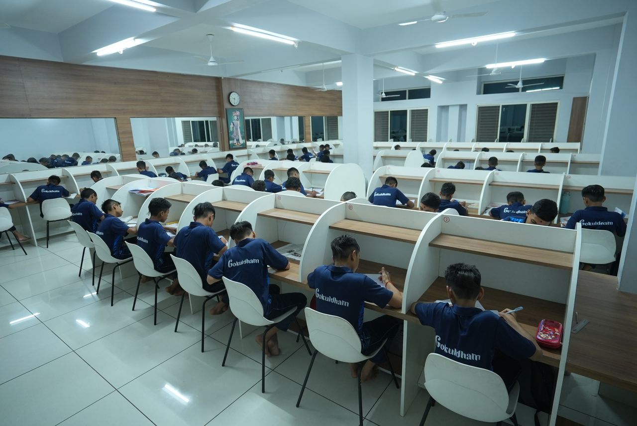 hero-img-02 Students studying in a modern library at Petlad. Focused educational setting fostering learning.